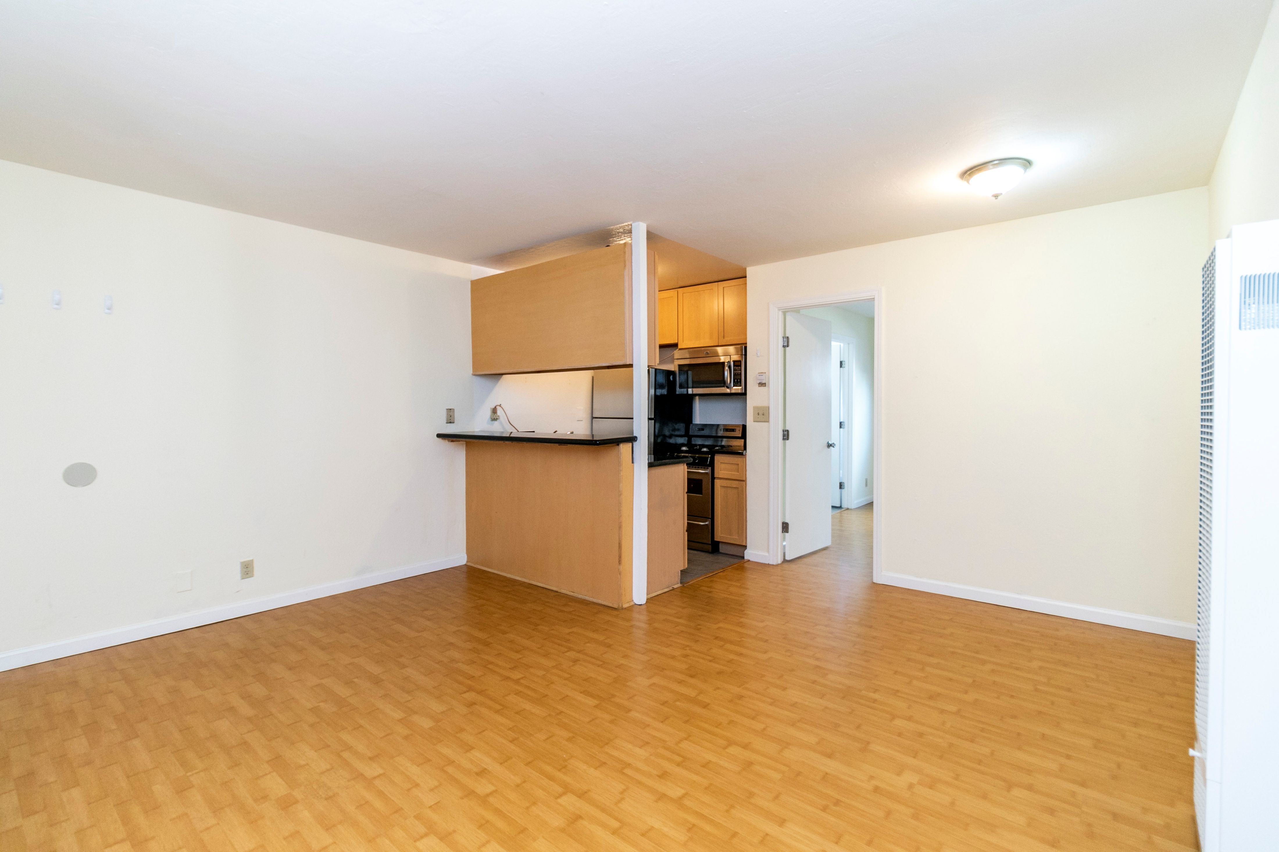 A kitchen area with wooden floors and cabinets.